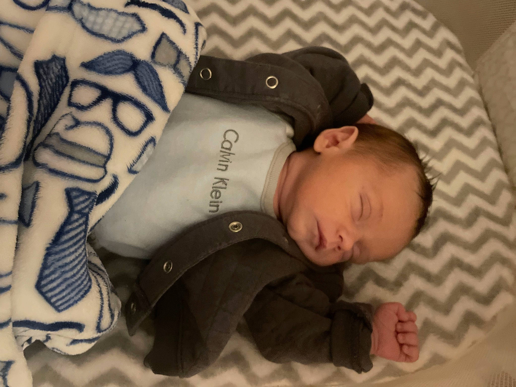 Rogan is registered to the contest to win money with this photo: arm, baby, baby_sleeping, baby_toddler_clothing, bedtime, child, comfort, design, gesture, head, linens, mammal, people, person, sitting, skin, sleeve, temporary_tattoo, toddler, wood