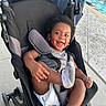 Isaiah joined the competition — help win amazing prizes! baby, child, stroller, smiling, happy, outdoor, poolside, swimming_pool, infant, portrait, sitting, fuzzy_socks, gray_clothing, diaper, harness, carriage, vacation, sunlight, pavement, playful