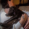 Shiva a rejoint le concours — aidez-le/la à gagner de superbes lots ! affection, black_dog, closeup, comfort, couch, cozy, dog, embrace, hand, home, indoor, intimate, peaceful, person, relaxing, rest, sleeping, tattoo, warm_lighting, white_sweater