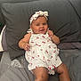 Ada-Violet is registered to the contest to win money with this photo: baby, child, smiling, headband, white_clothing, cherry_pattern, bed, pillow, happy, infant, cute, person, indoors, lying_down, skin, face, legs, socks, relaxed, playful