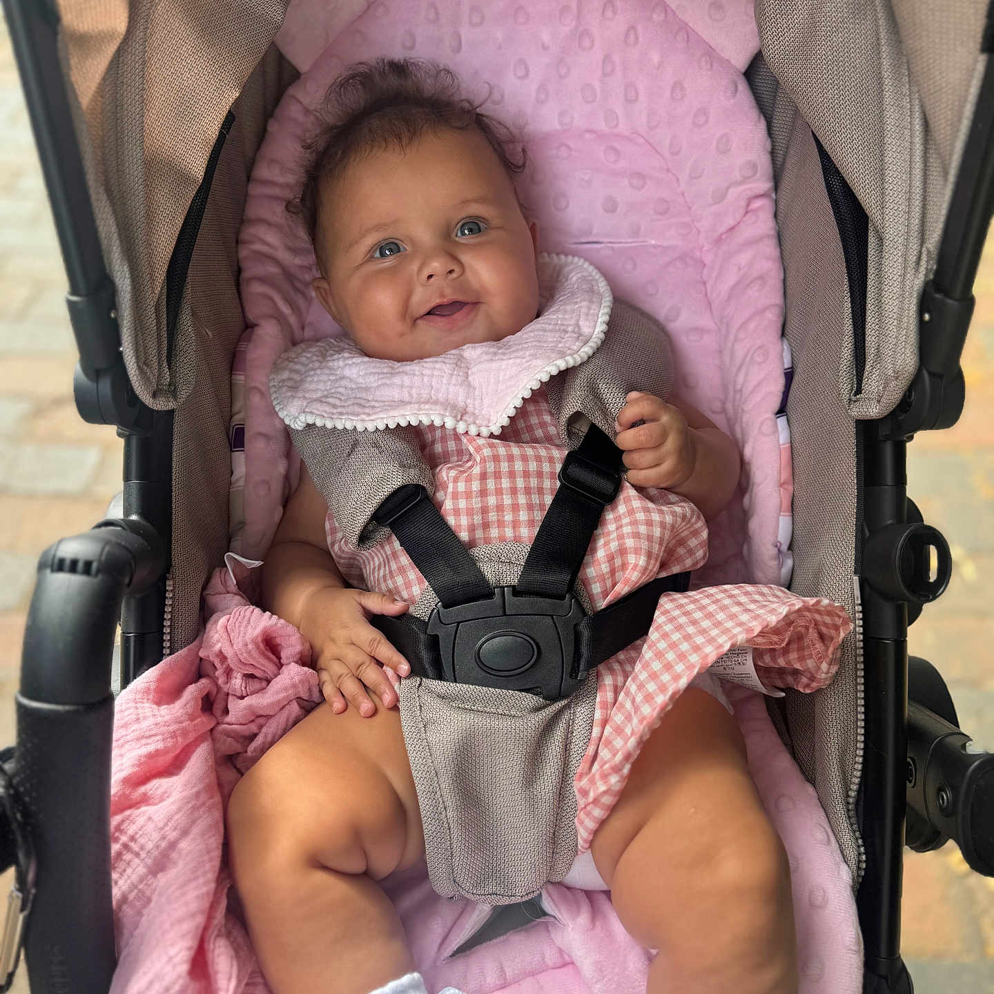 Ada-Violet is registered to the contest to win money with this photo: baby, baby_bib, baby_care, baby_clothing, baby_toys, child, curly_hair, cute, fabric, footwear, gingham_dress, happy, infant, outdoor, pink_blanket, seatbelt, smiling, soft_texture, stroller, white_socks
