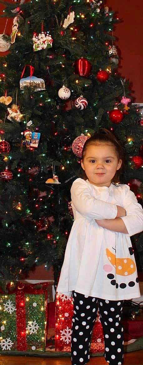 Ava joined the competition — help win amazing prizes! baby_toddler_clothing, black, christmas_ornament, christmas_tree, dress, evergreen, hair, happy, head, holiday_ornament, human_body, leaf, organ, ornament, person, photograph, red, sleeve, standing, white