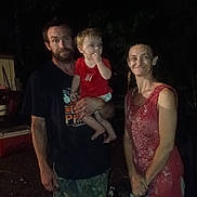 Rj is registered to the contest to win money with this photo: barefoot, beard, camouflage_pants, casual_clothing, child, dark_background, family, holding, man, night, outdoor, people, person, portrait, red_shirt, short_hair, smiling, standing, toddler, woman