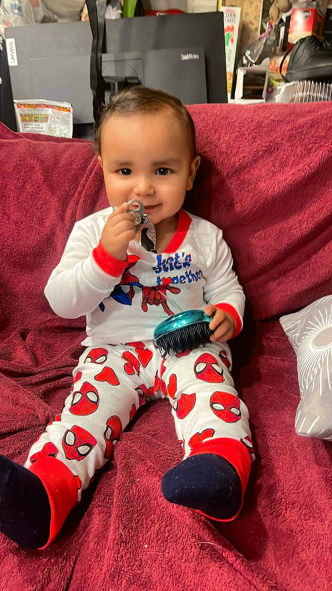 Jeremiah is registered to the contest to win money with this photo: baby, baby_toddler_clothing, carmine, child, christmas_eve, comfort, couch, flooring, happy, holiday, lap, nightwear, pattern, person, red, room, sitting, sleeve, smile, television