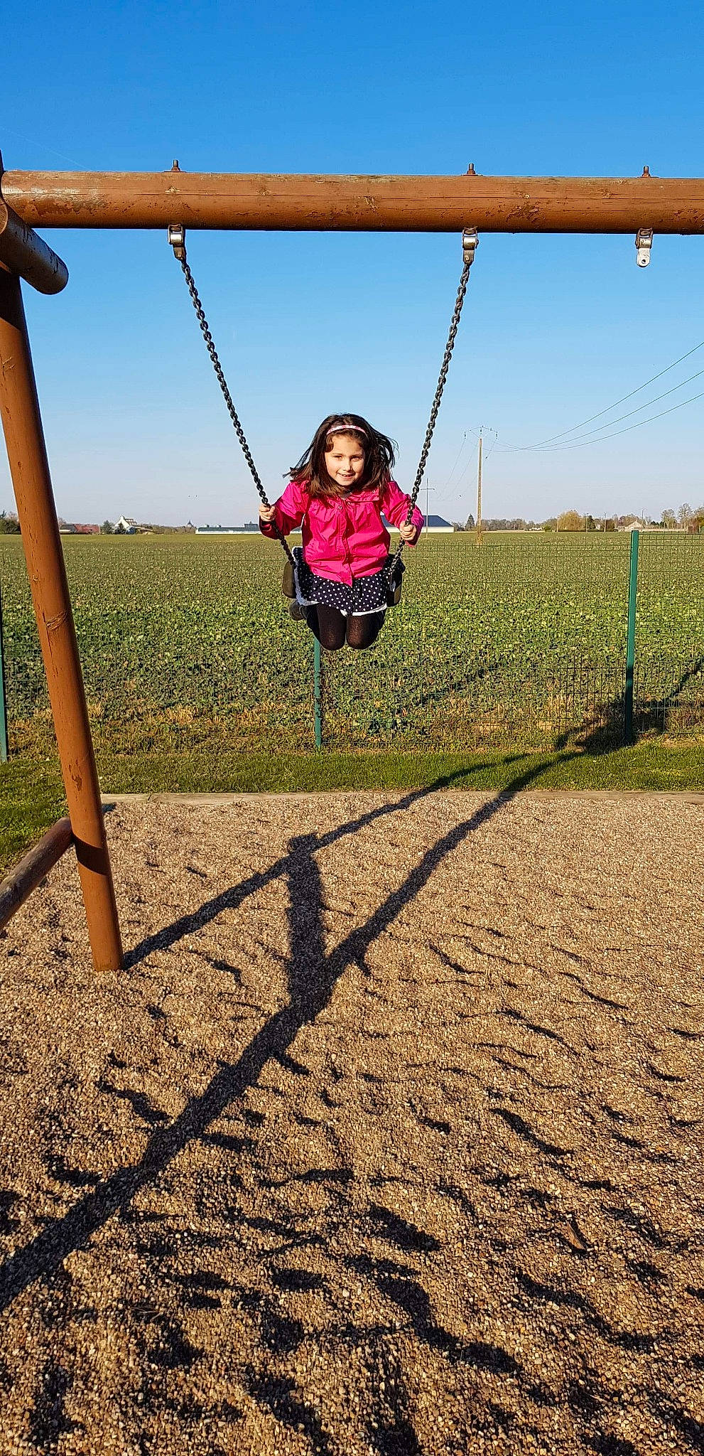 Lola participe au concours pour gagner de l'argent avec cette photo : child, city, field, fun, grass, happy, headwear, human_settlement, joy, landscape, leisure, outdoor_play_equipment, person, play, playground, public_space, recreation, sky, smile, swing