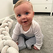 Logan is registered to the contest to win money with this photo: baby, child, infant, smiling, blue_eyes, white_clothing, striped_pants, sitting, carpet, plush_toy, home_interior, furniture, dresser, soft_toys, cute, indoors, person, happy, childhood, floor