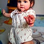 toddler, baby, child, crawling, onesie, floral_pattern, indoor, carpet, curious, young_child, person, furniture, soft_lighting, cute, small_hands, kneeling, expression, room, floor, earrings