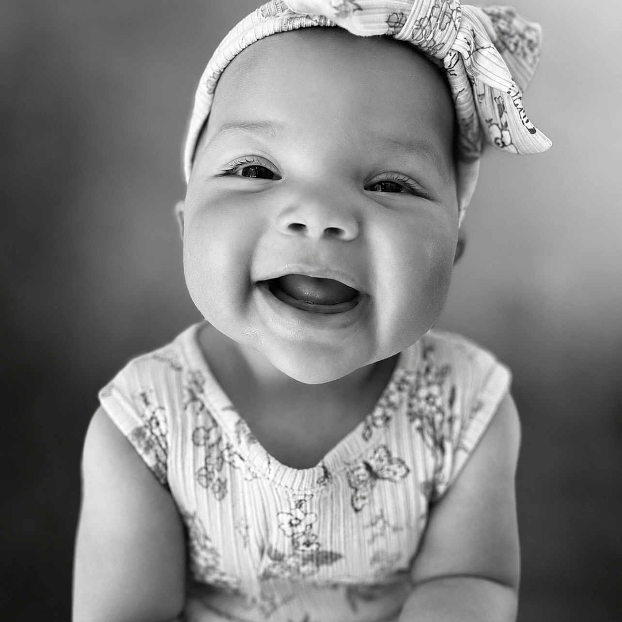 Love is registered to the contest to win money with this photo: baby, child, smiling, headband, portrait, black_and_white, happy, cute, infant, closeup, face, person, clothing, pattern, expression, young, sitting, indoors, cute_outfit, adorable