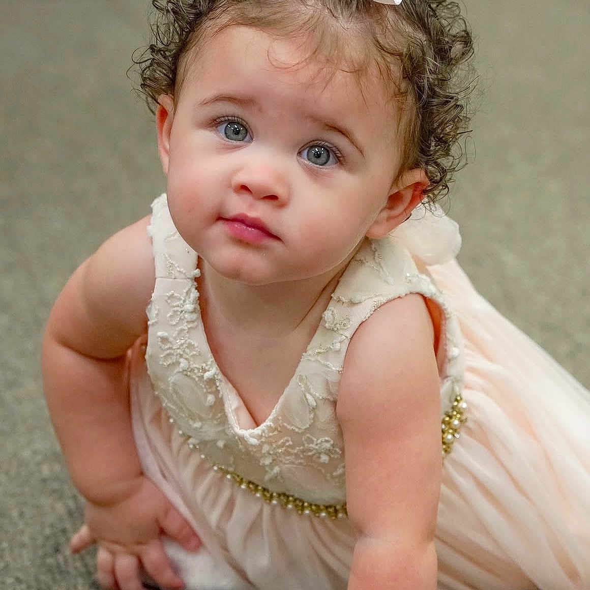 Alaya is registered to the contest to win money with this photo: baby, baby_girl, bow, carpet, child, crawling, curly_hair, cute, dress, expression, eyes, face, floor, hand, indoors, pearl, portrait, skin, toddler, white_dress