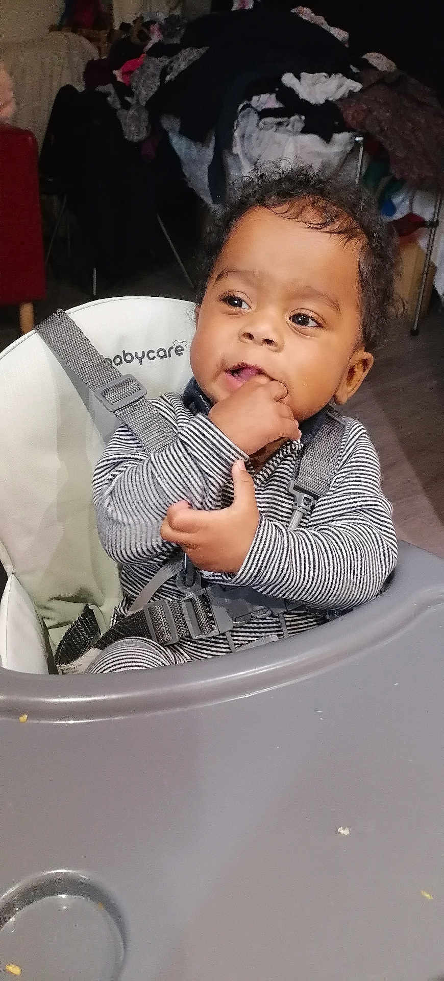 Wilden a rejoint le concours — aidez-le/la à gagner de superbes lots ! baby, high_chair, child, striped_clothing, indoors, curly_hair, teething, fingers_in_mouth, seatbelt, babycare_brand, face, person, furniture, tray_table, expression, young_child, casual, home, floor, clothing