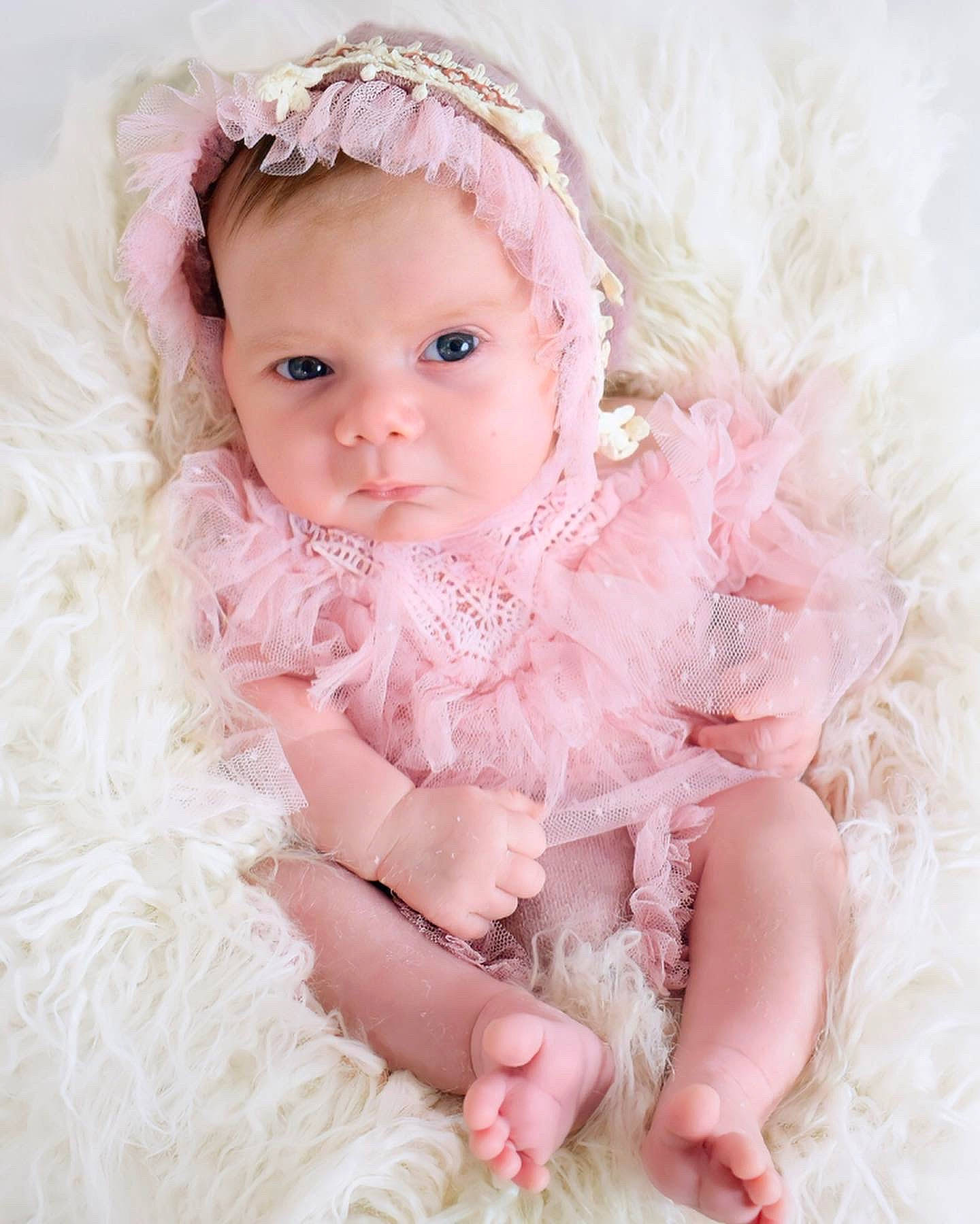 Skylah-maé is registered to the contest to win money with this photo: baby, baby_toddler_clothing, bridal_accessory, dress, embellishment, fashion_accessory, flash_photography, hair_accessory, happy, headband, headgear, headpiece, iris, peach, person, petal, pink, skin, sleeve, textile