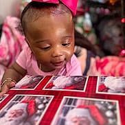 Shakayla is registered to the contest to win money with this photo: baby, child, pink_bow, gift_box, santa_claus, holiday, christmas, curious, indoors, portrait, close_up, cute, smiling, festive, celebration, person, young_child, bracelet, wearing, headwear