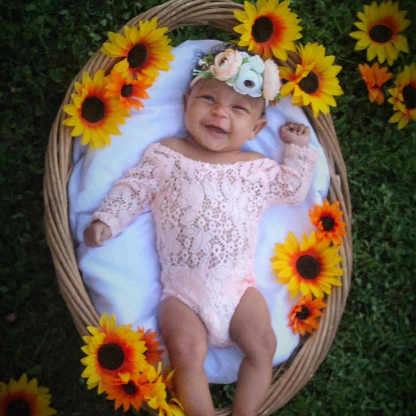 Amina joined the competition — help win amazing prizes! baby, baby_clothing, child, cute, floral, flower_crown, grass, greenery, happy, headband, infant, lying_down, nature, one_person, outdoor, pink_lace, portrait, smiling, sunflowers, wicker_basket