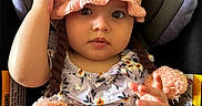 Ava is registered to the contest to win money with this photo: baby, child, hat, knit_hat, pom_poms, car_seat, floral_outfit, pink, cute, infant, portrait, hand, sitting, indoors, person, young_child, clothing, headwear, expression, seat