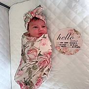 Ava is registered to the contest to win money with this photo: baby, birth_details, blanket, card, cute, face, floral_pattern, headband, indoors, infant, lying_down, newborn, peaceful, person, pink, portrait, quilted_bedding, soft, swaddle, white_background