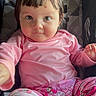 Ava joined the competition — help win amazing prizes! toddler, child, pink_clothing, pajamas, sitting, stroller, face, portrait, indoor, cute, baby, smile, person, young_child, curly_hair, playful, comfort, casual, closeup, happy