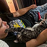 Walnut is registered to the contest to win money with this photo: affection, bed, black_shirt, blanket, casual_clothing, cat, cheek, comfort, feline, human, indoor, interaction, jeans, man, paw, playing, relaxed, resting, tabby_cat, tattoo