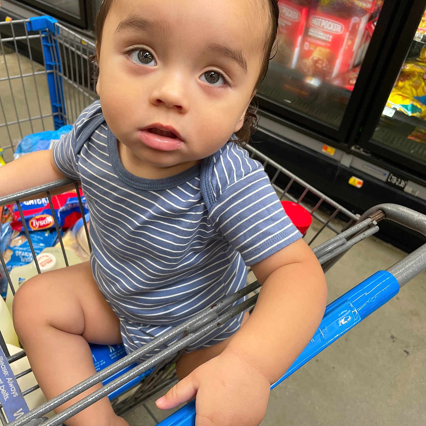 Julian Lucas Rojas is registered to the contest to win money with this photo: baby, child, clothing, eyes, face, floor, food, grocery, grocery_store, hand, person, product, retail, shopping, shopping_cart, sitting, store_interior, striped_shirt, supermarket, toddler