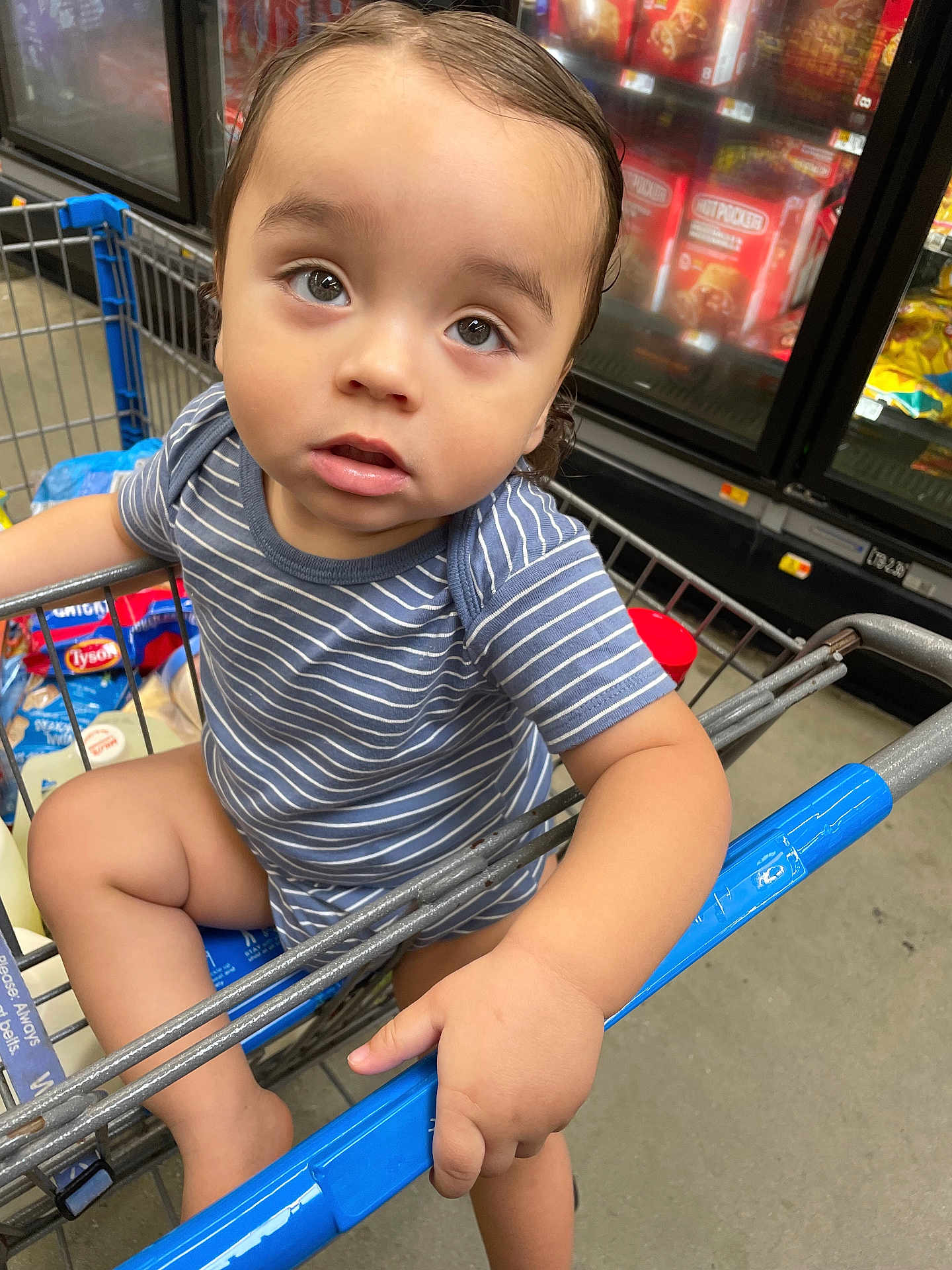Julian Lucas Rojas is registered to the contest to win money with this photo: toddler, child, shopping_cart, grocery_store, striped_shirt, baby, hand, face, eyes, floor, sitting, person, retail, supermarket, clothing, product, food, grocery, shopping, store_interior