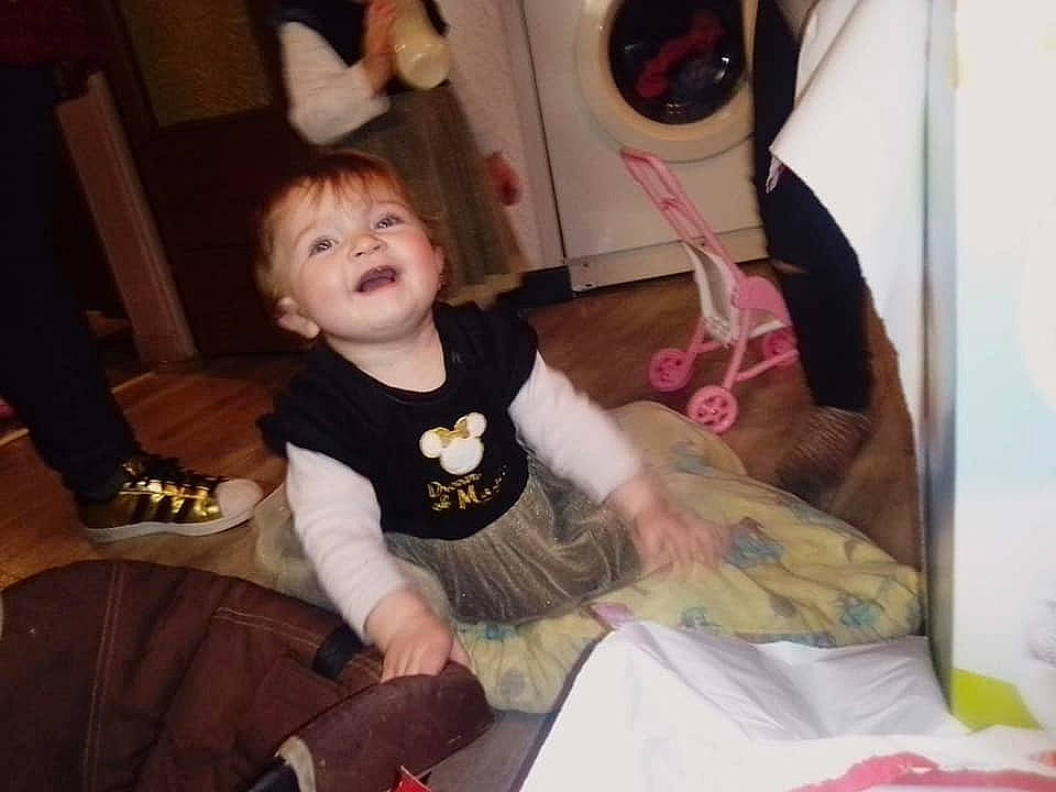 Carina participe au concours pour gagner de l'argent avec cette photo : baby, baby_toddler_clothing, child, comfort, event, facial_expression, fun, hairstyle, head, holiday, human_body, lap, living_room, mammal, person, room, sitting, subwoofer, t_shirt, toddler