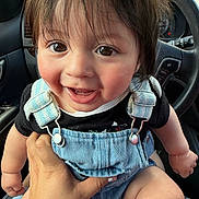 Aarón joined the competition — help win amazing prizes! baby, child, smiling, denim_overalls, black_shirt, car_interior, steering_wheel, hand, person, cute, happy, closeup, infant, baby_face, seat, window, skin, hair, eyes, tooth