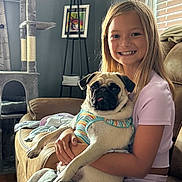 Stella joined the competition — help win amazing prizes! girl, pug, dog, smile, couch, living_room, cat_tree, window_blinds, child, pet, pet_harness, furniture, happy, indoor, person, sitting, light, portrait, casual_clothing, home_decor