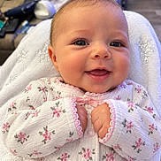 Eleanor joined the competition — help win amazing prizes! baby, infant, child, smiling, portrait, close_up, floral_clothing, onesie, white_blanket, lying_down, indoor, face, eyes, mouth, hands, cozy, happy, soft_lighting, photography, family_moment