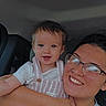 adult, arm, car_interior, casual_wear, child, clothing, face, glasses, hair, happy, holding, indoor, light, person, portrait, seat, smile, toddler, together, young_adult