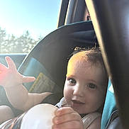 Serenity joined the competition — help win amazing prizes! baby, child, car_seat, bottle, hand, sunlight, window, sky, trees, smile, face, infant, vehicle_interior, seatbelt, person, young_child, daylight, candid, portrait, cute