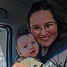 baby, car, casual, clothing, face, glasses, hair, hand, happy, holding, indoor, light, person, portrait, seat, shadow, smile, toddler, window, woman