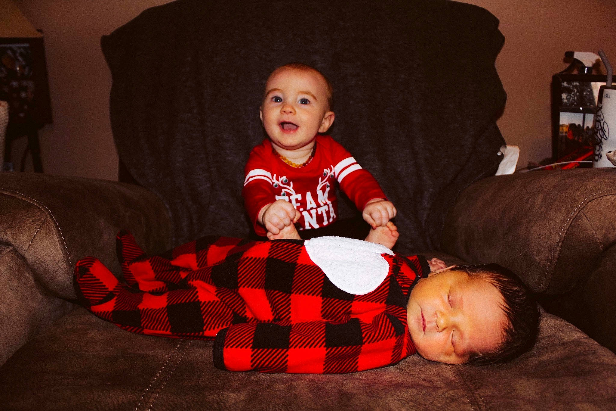 Noel joined the competition — help win amazing prizes! baby, baby_toddler_clothing, comfort, couch, fun, holiday, lamp, lap, living_room, pattern, person, pillow, plaid, red, sleeve, smile, sock, t_shirt, tartan, thigh