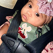 Betsy joined the competition — help win amazing prizes! baby, infant, child, car_seat, safety_harness, pink_headband, flower, pearl, portrait, close_up, wide_eyes, pout, sitting, green_clothing, pink_clothing, indoors, vehicle, securely_strapped, face, photography