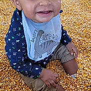 Dontae joined the competition — help win amazing prizes! baby, background, bib, casual_wear, child, clothing, corn_kernels, cute, dinosaur, face, feet, hands, happy, indoor, person, playful, sitting, smiling, texture, toddler