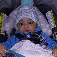 Nicholas is registered to the contest to win money with this photo: baby, blanket, blue_clothing, car_seat, child, cute, expression, eyes, face, footwear, hands, hat, indoor, infant, pacifier, pom_pom, safety_harness, seated, striped_pants, winter_wear
