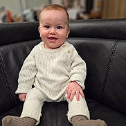 Milan a rejoint le concours — aidez-le/la à gagner de superbes lots ! baby, infant, smiling, sweater, knitwear, socks, leather_sofa, couch, indoor, portrait, sitting, hands, eyes, cheeks, furniture, cozy, happy, button, legs, cute