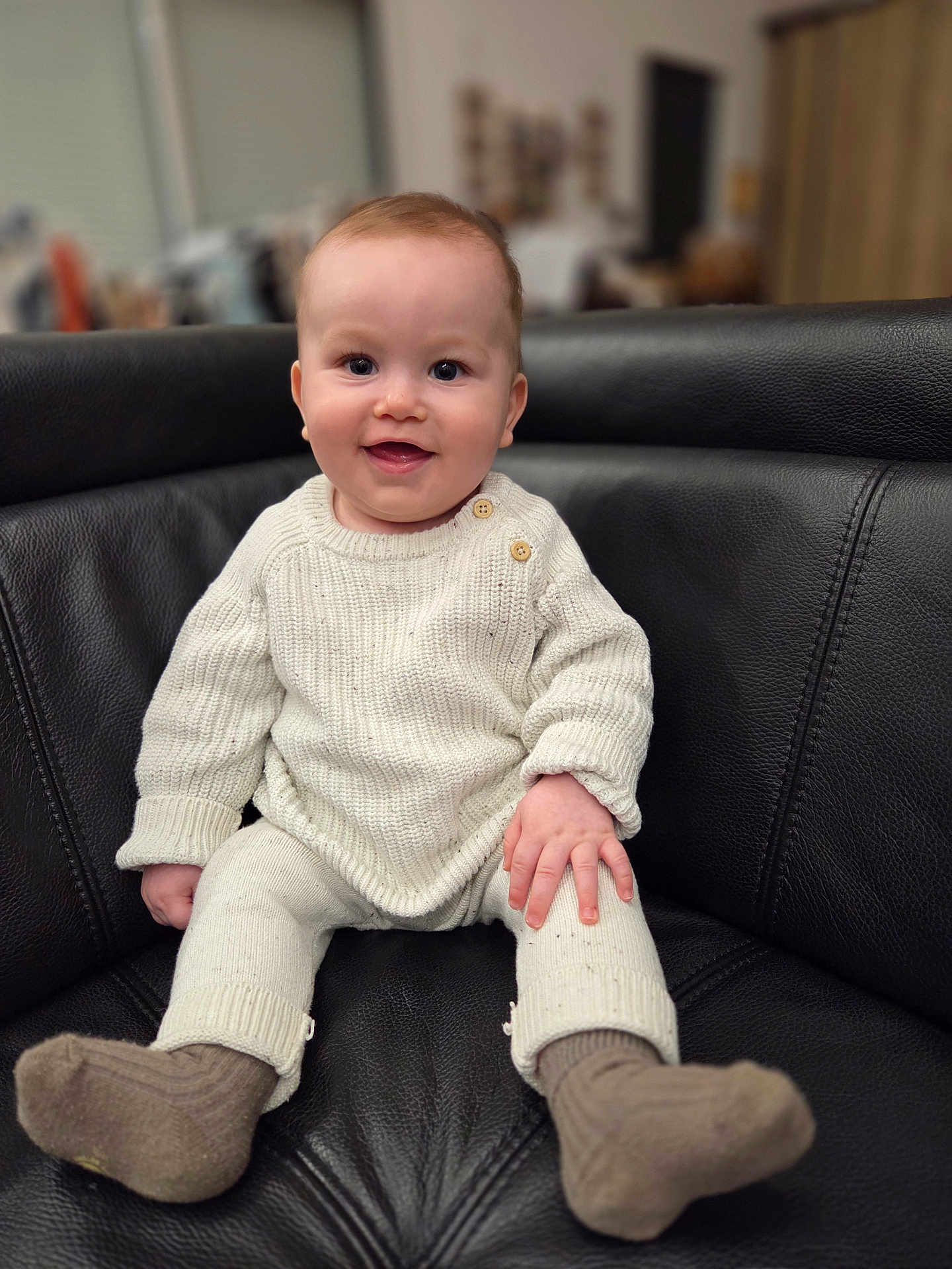 Milan a rejoint le concours — aidez-le/la à gagner de superbes lots ! baby, infant, smiling, sweater, knitwear, socks, leather_sofa, couch, indoor, portrait, sitting, hands, eyes, cheeks, furniture, cozy, happy, button, legs, cute