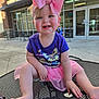 toddler, child, smiling, pink_bow, purple_shirt, butterfly, outdoor, table, barefoot, happy, person, daylight, casual, building, window, concrete, seat, playful, cute, baby
