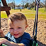 child, toddler, swing, playground, smile, happy, outdoor, park, green, clothing, daylight, trees, grass, blue_sky, person, seat, play, young_child, fun, nature