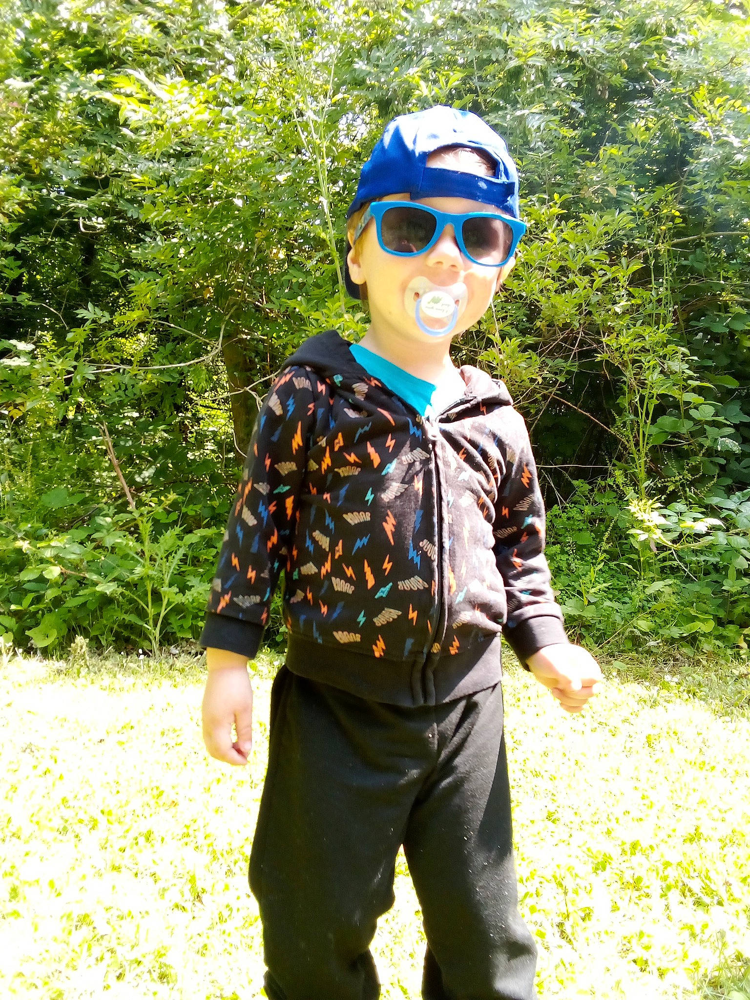 Guilio participe au concours pour gagner de l'argent avec cette photo : baseball_cap, cap, cool, electric_blue, eyewear, glasses, goggles, grass, headgear, headwear, leisure, people_in_nature, person, personal_protective_equipment, plant, sleeve, smile, sunglasses, t_shirt, toddler