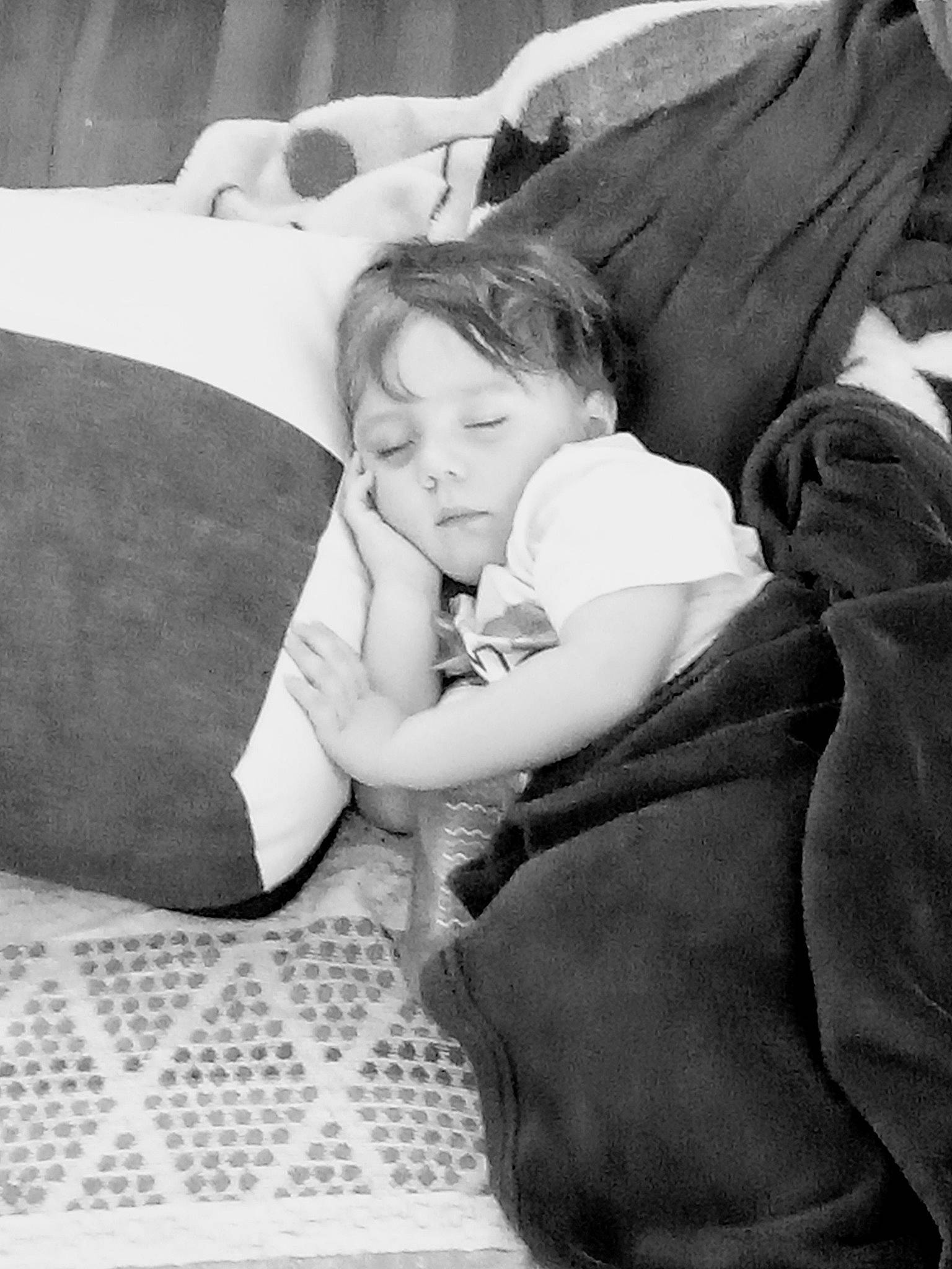 Guilio participe au concours pour gagner de l'argent avec cette photo : baby, bedding, bedtime, black, black_and_white, comfort, couch, fun, gesture, grey, happy, human_leg, lap, linens, monochrome, monochrome_photography, person, room, sitting, style