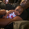baby, adult, holding, phone, indoor, person, closeup, relaxing, casual, black_clothing, infant, portrait, family, candid, resting, comfort, interaction, face, hands, light