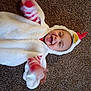 Corbin is registered to the contest to win money with this photo: baby, child, costume, chicken, carpet, smile, happy, cute, infant, clothing, hood, playful, lying_down, arms, fun, indoors, person, young, expression, joy