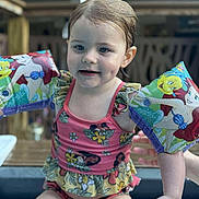 Oraya is registered to the contest to win money with this photo: arm_floaties, cartoon_characters, child, cute, dimples, floaties, fun, outdoor, person, pink_swimsuit, playful, pool, sitting, skin, smile, summer, swimming, toddler, water, wet_hair