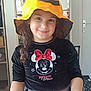 black_shirt, casual_clothing, child, curly_hair, cute, door, fashion, furniture, girl, happy, hat, home, indoor, long_hair, minnie_mouse, person, portrait, pumpkin_hat, smiling, wall