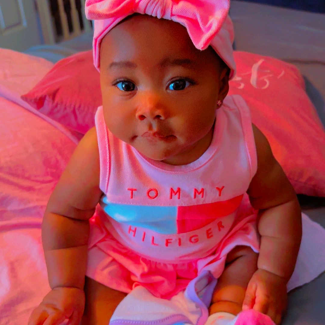 Mulani joined the competition — help win amazing prizes! baby, bed, child, clothing, cute, face, fashion, headband, indoor, infant, person, pillow, pink_bow, portrait, sitting, skin, smiling, socks, tommy_hilfiger, young_child