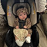 baby, infant, car_seat, leopard_print, headband, blanket, socks, indoor, child, young_child, seatbelt, cushion, person, clothing, cute, portrait, baby_clothes, fabric, home, car_seat_cover
