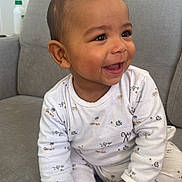 Khadim participe au concours pour gagner de l'argent avec cette photo : baby, infant, child, smiling, laughing, sitting, couch, sofa, onesie, pajamas, hands, feet, toes, eyes, hair, portrait, indoor, living_room, looking_right, cute