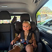 Blake is registered to the contest to win money with this photo: toddler, child, car_seat, car_interior, seatbelt, blonde_hair, blue_eyes, shorts, bare_chest, window, car_window, car_headrest, car_door, vehicle, seat, people_outside, outdoor_scene, daylight, passenger, safety_harness