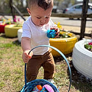 Liam joined the competition — help win amazing prizes! child, toddler, easter_egg, basket, outdoor, grass, toy, spring, colorful, egg_hunt, shiny, curious, pants, white_shirt, sunlight, decor, flower, play, daytime, activity
