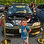 Liam joined the competition — help win amazing prizes! toddler, child, car, engine, hood_open, parking_lot, golden_stanchions, blue_shirt, mickey_mouse, shorts, shoes, people, trees, daylight, outdoor, vehicle, person, smile, cute, casual_clothing